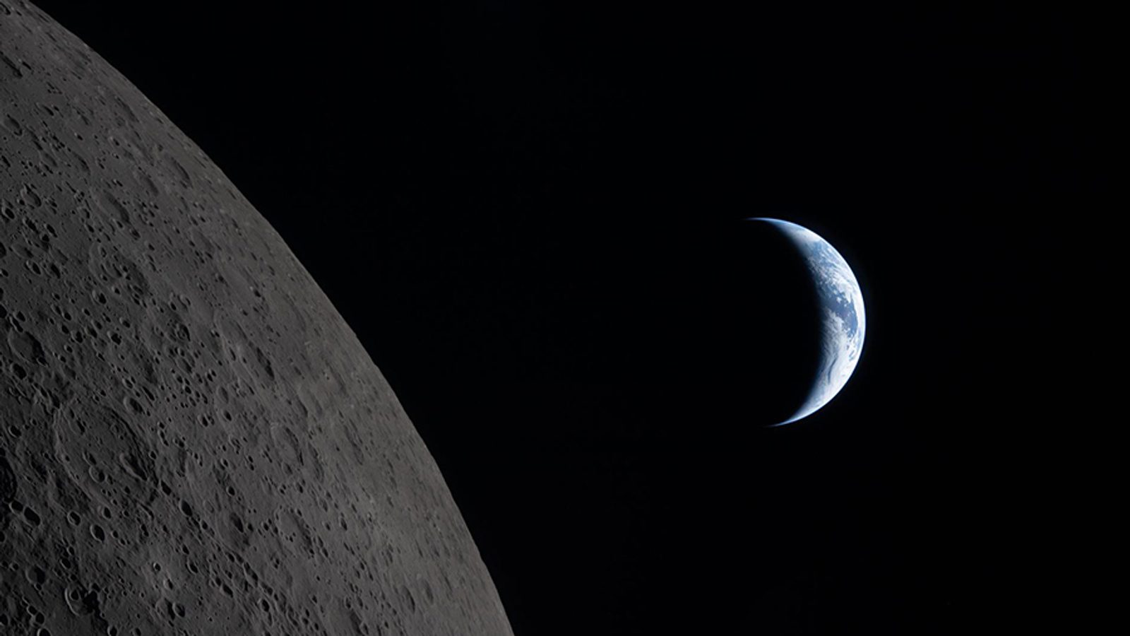 Gros plan de la surface grise de la Lune avec un fin croissant de Terre visible dans l'obscurité de l'espace.